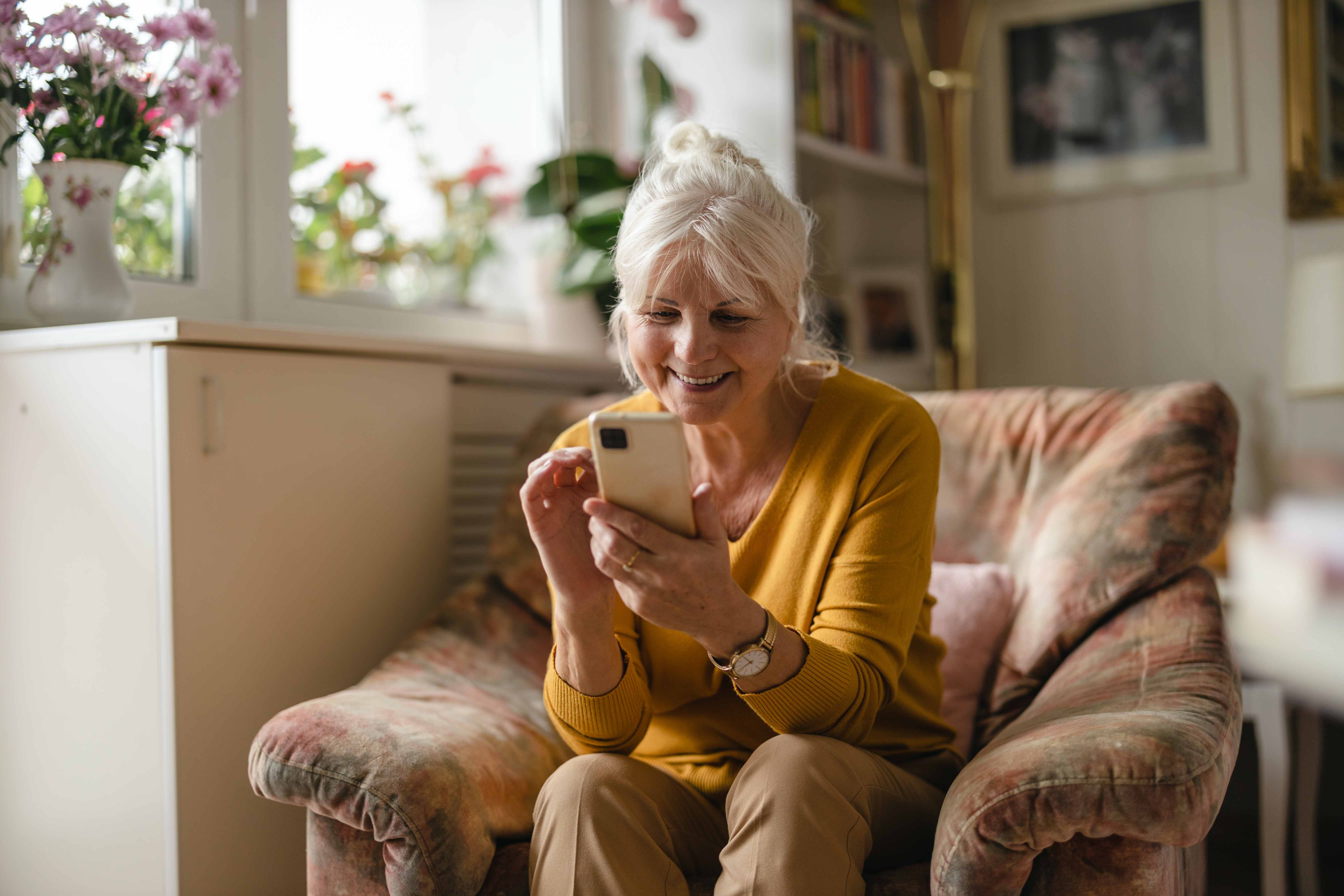 Senior woman smiling while using his smartphone